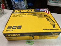 Closed yellow and black DeWalt box showing model DW272 drywall screw gun with USA flag logo and guaranteed tough slogan.