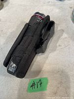 Flashlight in black nylon holster showing side and multitool compartments