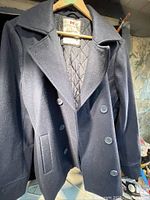 Front view of dark navy blue wool winter jacket with double-breasted buttons, collar and pockets.