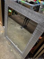 Front view of large rectangular wall mirror showing silver textured frame and beveled mirror surface.