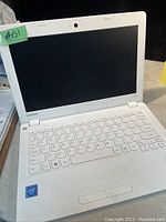 Front view of white Lenovo laptop showing keyboard and screen, Intel sticker present on palm rest. Laptop appears used with some dirt visible.