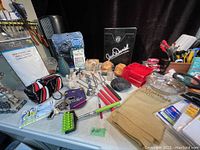 Full overview of lot items on table including utensils, figurines, storage organizer, branded box and bags.