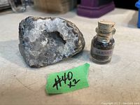 Quartz geode and bottle of garnet stones displayed on table with label