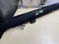 Full view of the Vizio sound bar showing the fabric covering, wires and general length.