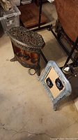 Photo showing both an ornate antique metal space heater with copper elements and a decorative frame with two Bluetooth speakers attached.