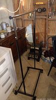 Full view of metal clothes rack in a room, showing its structure and base with wheels.