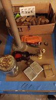 Overview of the assorted vintage lighters, glass pipe, small nails, and boxed items on a table.