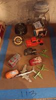 Overview of the vintage toys including toy vehicles, planes, metal target game, and glass jar with matchbooks.