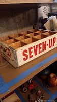 Wooden 7 Up crate showing 'SEVEN-UP' in red letters on one side, with 24 compartments for bottles.