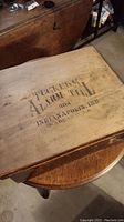 Top view of vintage wooden box lid with stenciled text 'TUCKER'S ALARM TILL 500 INDIANAPOLIS, IND. MADE IN U.S.A.' showing overall condition and text detail.