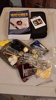 Overall collection showing the complete watch repair kit with watches, tools, parts, and book.