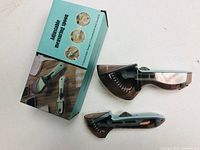 Two adjustable measuring spoons next to retail box with usage instructions and images