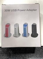 Box showing 30W USB power adapter options in multiple colors (red, grey, blue, black) as a vertical tower with six USB ports.