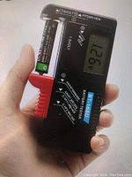 Digital BT-168 battery tester showing 1.251 voltage reading on LCD screen with sliding red probe holding AA battery