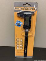 Front view of the FineSource Carbon Fiber Composites Digital Caliper in packaging with included battery visible.