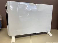 Side view of De'Longhi slim panel heater showing white metal body with small dents and embossed De'Longhi branding.