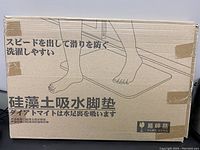 Cardboard box packaging with Japanese text and drawing of feet on mat, indicating product usage for water absorption and anti-slip properties.