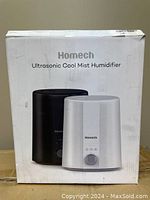 Box of Homech Ultrasonic Cool Mist Humidifier showing printed images of white and black humidifier models and branding details.