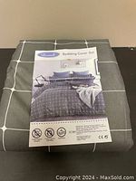 Folded Levesolls bedding cover set in grey with white square grid pattern and printed label showing the product image and features.