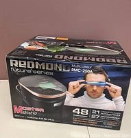 Box front showing Redmond RMC-250A multi-cooker image and branding with features like 21 automatic programs, 48 programs total, 800W power, 4.2 Qt volume.
