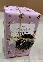 Bar of Castelbel Wild Lavender soap wrapped in lavender-themed paper with gold bees, tied with gold string and tag, showing front label