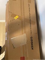 Cardboard box with label showing model number ASNG073 and description 'Fabric 13 Drawer-High Storage Cabinet / WXF'