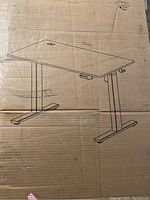 Front of cardboard box showing line drawing of desk