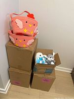 Whole lot showing stacked boxes with pink chicken-shaped baskets on top and box with stuffed bunnies at side