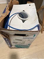 View of original cardboard box containing mostly full spool of blue LANmark 1000 Cat6 cable with some cable visible outside the box
