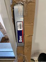 Close-up of box showing BON brand label on side of metal paver screed piece within packaging.