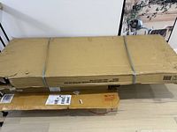 Two sealed cardboard boxes strapped with plastic bands containing bed frame components