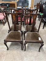Four wooden dining chairs shown from front, with visible inlay decoration on the backrests, cabriole legs, and brown padded tops needing cleaning.