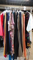 Rack of assorted women's clothing including pants and sleeveless blouses, various colors and patterns