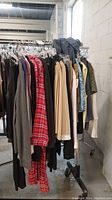 Photo of assorted clothing on rack showing variety including plaid and neutral colored shirts