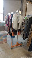 The clothing rack loaded with various garments on hangers in a warehouse environment.