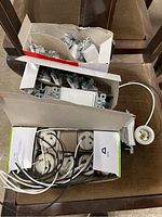 Box with Legrand rocker light switches stacked inside with metal mounting frames and some loose light switches.