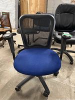 Front view of adjustable office chair showing blue seat cushion, black mesh backrest, armrests, and caster wheels.