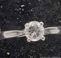 Top-down view of ring showing round brilliant diamond in four-prong setting and white gold shank