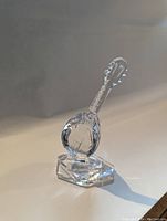 Clear crystal mandolin sculpture figurine on hexagonal base, detailed faceted design.