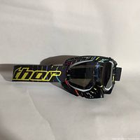 Side view of Thor ski goggles showing the multicolor patterned frame and black strap with yellow Thor branding.