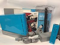 Clear view of entire blue Nintendo Wii console bundle with power adapter, AV cable, blue Wii Remote with Nunchuk, The House of the Dead Overkill game, and manuals laid out for display.
