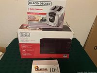 Both new boxed appliances: Black+Decker microwave oven and toaster stacked on a table.