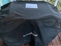 Grill fully covered by Blackstone-branded black vinyl cover.