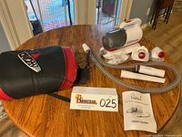 Casada foot massager with remote and power adapter on table next to pet grooming vacuum with attachments and user guide