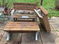 Outdoor patio loveseat and bench constructed of cedar wood and plastic legs, shown on concrete patio with surrounding grass and leaves.