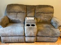 Front view of the gray electric recliner loveseat showing fabric texture, center console with two cup holders, padded cushions and armrests.