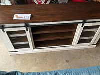 Front angle showing full TV stand with barn doors closed and side shelving visible