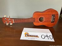 Front view of handcrafted Hohner ukulele showing body, sound hole, and part of fretboard with tuning pegs.