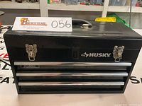 Front view of black metal Husky toolbox with three metal drawers and latch locks