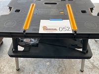 Top view of black Keter work bench with yellow tool support tracks and cutout handles, showing minor surface wear.